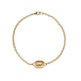 Gold bracelet with a bear charm on a white background