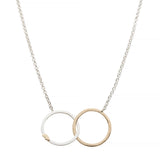 Necklace with two interlocking rings, one sterling silver with a 14k yellow gold bear  and one gold, on a white background
