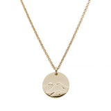 Gold circle pendant with mountains and a bear on a gold chain on a white background
