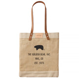 Beige tote bag with brown leather handle and black text on a white background