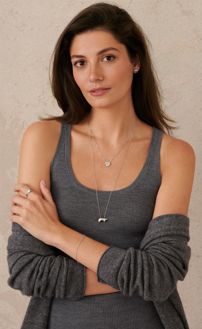 woman wearing a long bear necklace with a shorter heart necklace