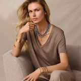 Woman wearing layered necklaces and bracelets on a neutral background