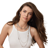 Woman wearing a white tank top and multiple silver and gold pieces of jewelry  on a white background